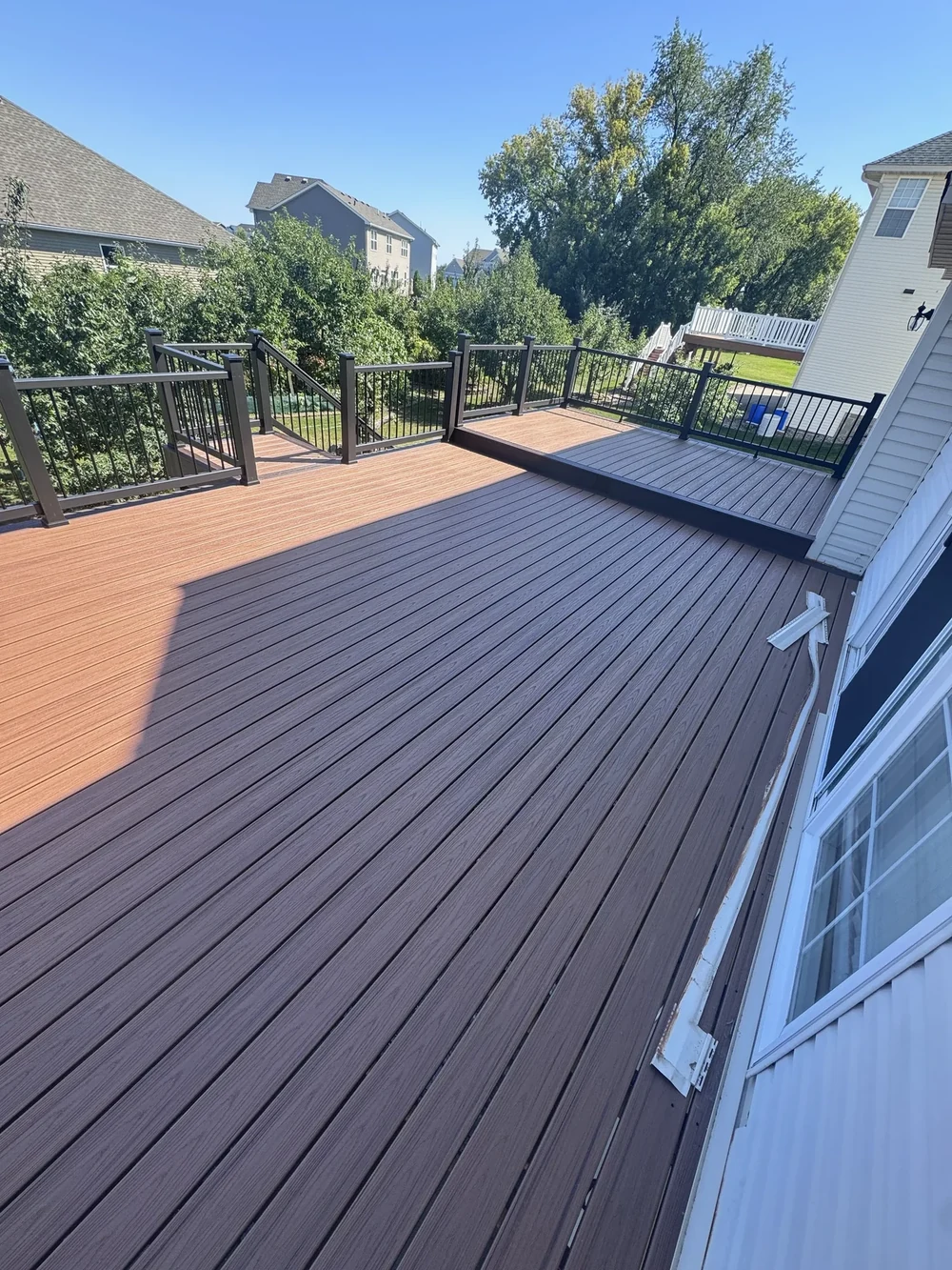 Composite deck renovation with contrasting picture-frame border and black railing completed by Home Improvement Partners in Savage, Minnesota